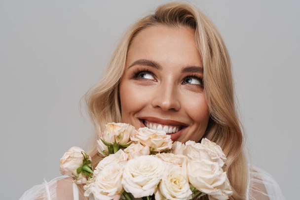 Beautiful happy smiling while posing with roses isolated over grey background - 写真・画像