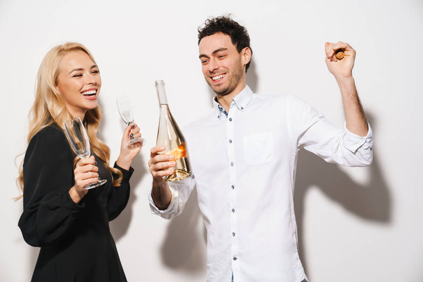 Feliz pareja romántica sonriendo mientras bebe champán aislado sobre fondo blanco - Foto, Imagen