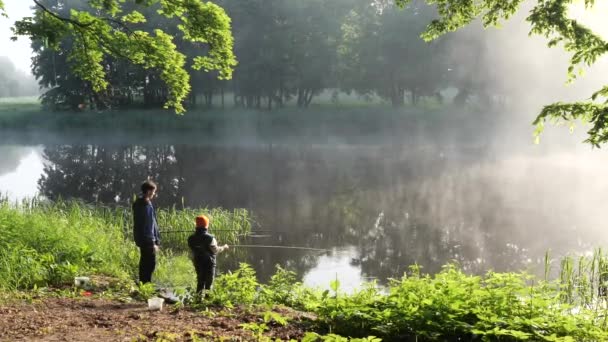 όμορφη τοποθεσία στη λίμνη πρωί ομίχλη παιδιά αλιείας με καλάμια ψαρέματος - Πλάνα, βίντεο