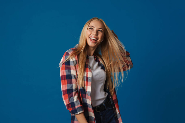 Veselé krásné blondýny dívka s úsměvem při tanci na kameře izolované přes modré pozadí - Fotografie, Obrázek