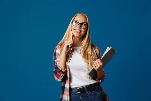 Cheerful blonde caucasian girl posing with clipboard isolated over blue background - Photo, Image