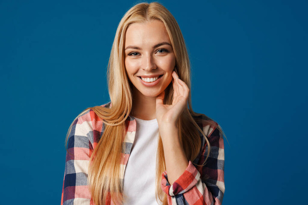 Blonde young happy woman smiling and looking at camera isolated over blue background - Foto, immagini