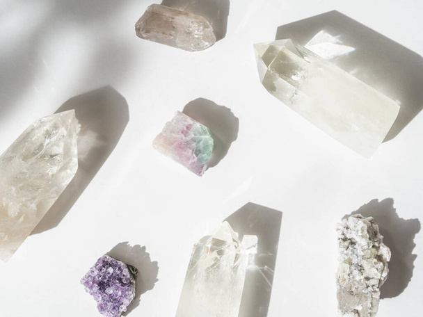 Güneş ışığının gölgeleriyle beyaz arkaplandaki mineral kristallerinin toplanması - Fotoğraf, Görsel