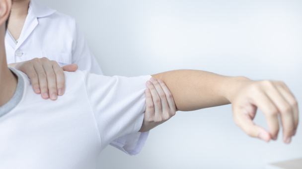 Fysiotherapie, Vrouwelijke fysiotherapeut behandelt armen en schouders pijn voor een mannelijke patiënt aanwezig in kliniek, Botregeling, Niet-chirurgische medische behandeling, Moderne medische technieken. - Foto, afbeelding