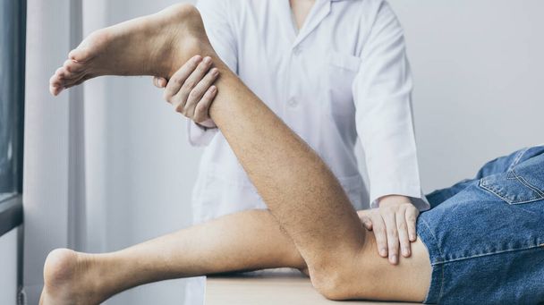 Fysiotherapie, Vrouwelijke fysiotherapeut behandelt benen en heupen pijn voor een mannelijke patiënt aanwezig in kliniek, Botregeling, Niet-chirurgische medische behandeling, Moderne medische technieken. - Foto, afbeelding