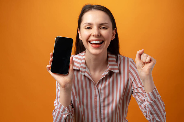 Happy smiling young woman showing you black smartphone screen with copy space - Foto, Imagem