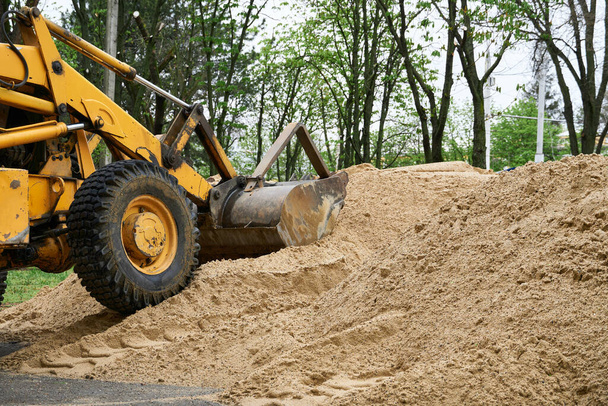 Traktor oder Planierraupe arbeitet mit einem Sandhaufen für den Bau - Foto, Bild