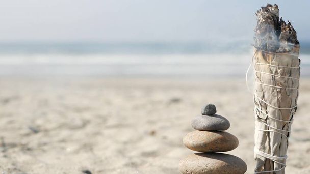 Balanço de rocha na praia do oceano, pedras empilhar por ondas de água do mar. Pirâmide de seixos, pau de mancha de salva. - Foto, Imagem