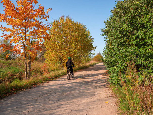 Carrera de ciclistas del pueblo a lo largo de un polvoriento camino rural. Una vista real desde atrás. - Foto, Imagen