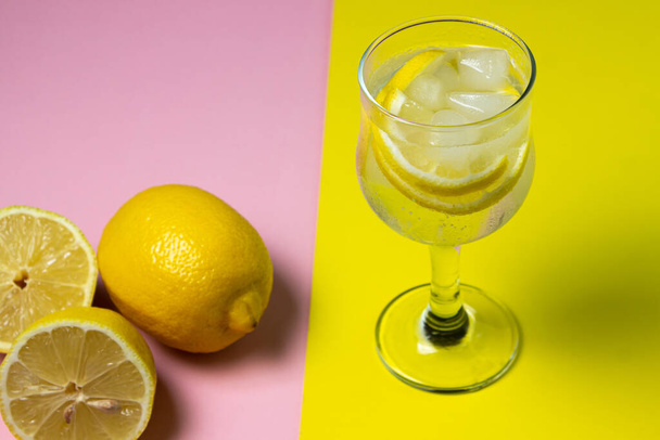 Frissítő koktél jéggel és citrommal, színes háttérrel. Alkoholmentes koktél. - Fotó, kép