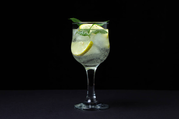 Refreshing cocktail with ice, lemon and mint on a black background. Non-alcoholic cocktail. - Φωτογραφία, εικόνα