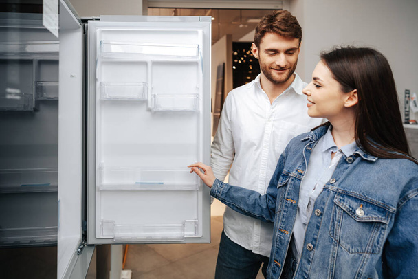 Young couple selecting new refrigerator in household appliance store - Zdjęcie, obraz