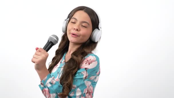 vrolijk kind zanger luisteren muziek in koptelefoon en zingen lied in microfoon, vocale school - Video