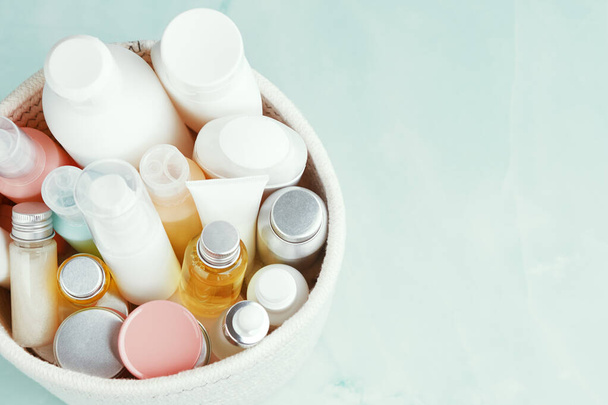Cesta blanca textil y muchas botellas de cosméticos diferentes, tubos, frascos. Cuidado de la piel, tratamientos de spa. - Foto, Imagen