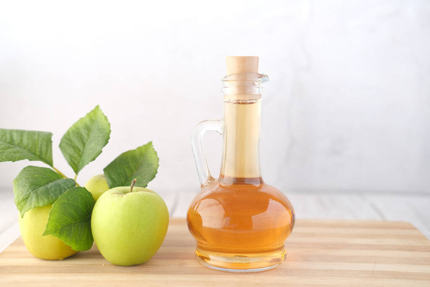 テーブルの上に新鮮な緑のリンゴとガラス瓶のリンゴ酢  - 写真・画像