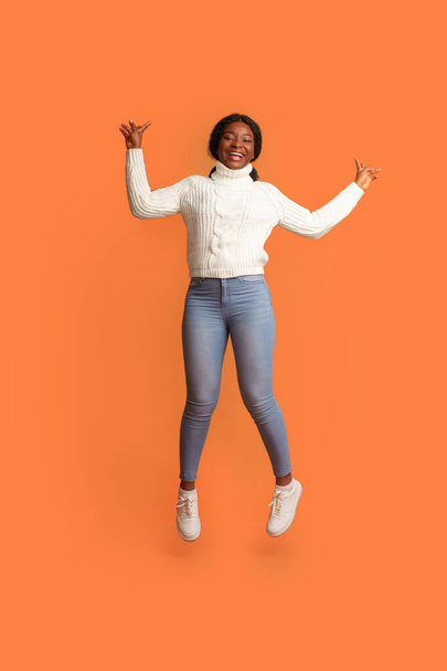 陽気な気分。幸せな若い黒の女性は手を上げ空気中でジャンプ - 写真・画像