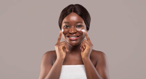 幸せな笑顔アフリカ系アメリカ人女性の美しさの肖像顔クリームを適用 - 写真・画像