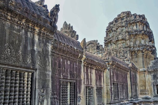 Фрагмент стародавнього камбоджійського храму проти блакитного неба. Вітер'яні стіни зберегли різьблення, прикраси і барельєфи. Ангкор. - Фото, зображення
