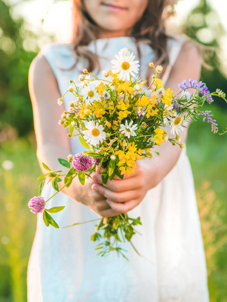 Child girl with wildflowers in summer. Selective focus. Nature. - Foto, Imagem