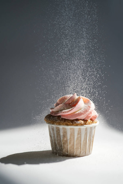 Cupcake on a dark background, which is sprinkled on top. - Photo, Image