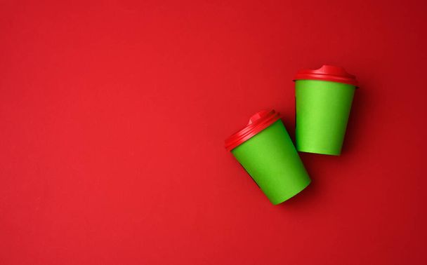 two green paper cups with a plastic lid on a red background, top view, copy space - Foto, Imagem