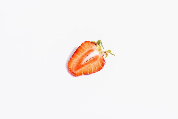Fresh ripe half strawberry isolated on white background. Sweet summer fruit, healthy food. A modern hard light, dark shadow, top view - Fotó, kép
