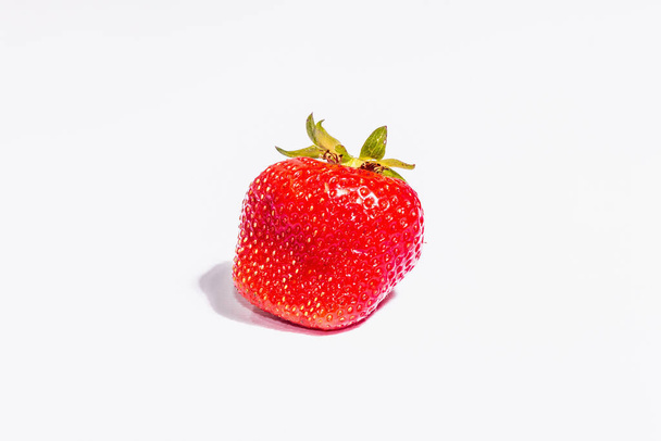 Свежая спелая клубника выделена на белом фоне. Сладкие летние фрукты, здоровая еда. Современный жесткий свет, темная тень - Фото, изображение