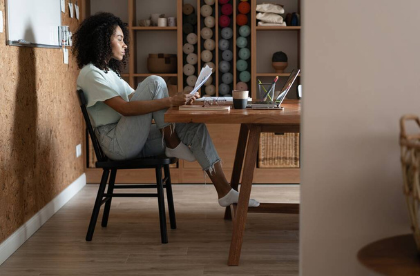 Millennial african american businesswoman reading paper at her workplace in office. - 写真・画像