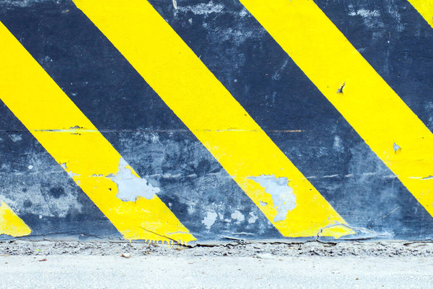Κίτρινες-μαύρες ρίγες σε τσιμεντένιο φράχτη κοντά στην εθνική οδό - Φωτογραφία, εικόνα