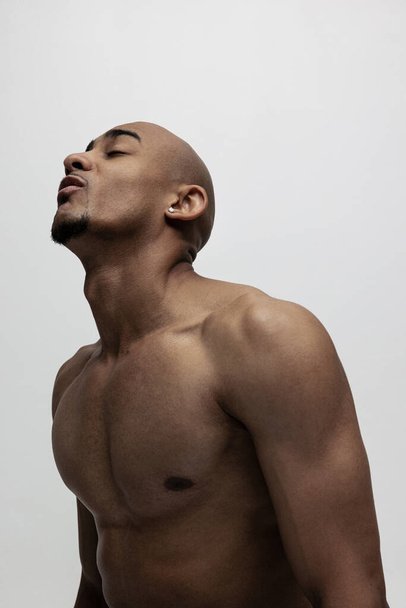 Primer plano guapo musculoso hombre africano posando aislado sobre fondo blanco. Concepto de belleza, cosméticos, spa. - Foto, imagen