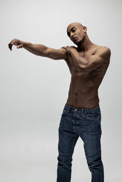 Ritratto di giovane uomo africano muscoloso, modello di moda isolato su sfondo bianco. Dolcezza - Foto, immagini