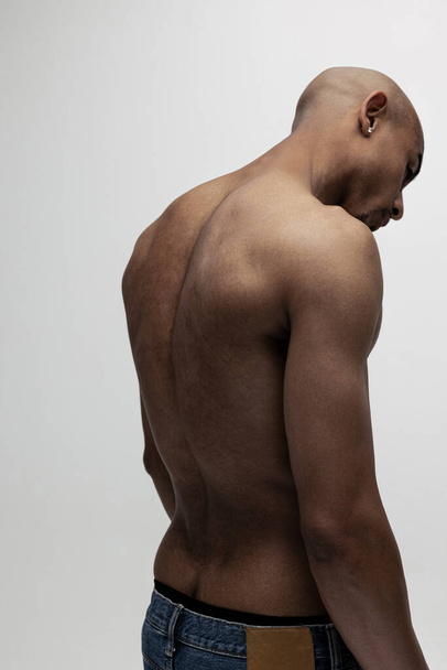 Retrato de un joven hombre africano musculoso, modelo de moda aislado sobre fondo blanco. Vista trasera - Foto, imagen