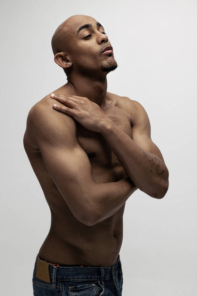 Joven hombre africano guapo musculoso posando aislado sobre fondo blanco. Concepto de belleza, cosméticos, spa. - Foto, imagen