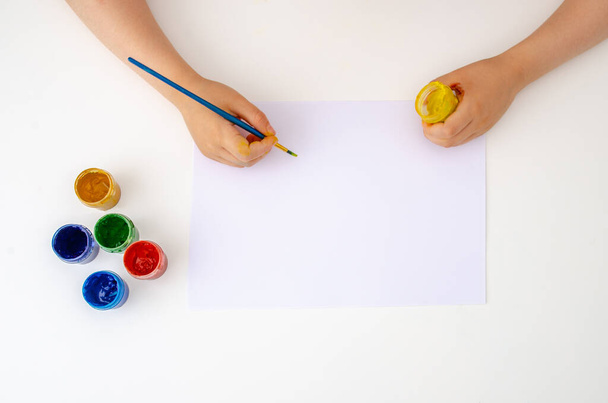 Bolígrafos infantiles dibujan en una hoja de papel en blanco sobre un fondo blanco. - Foto, imagen