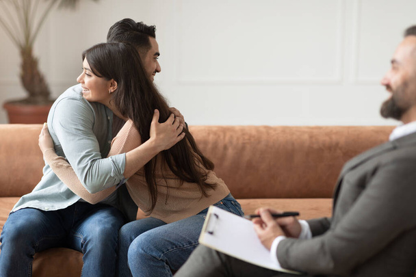 Szczęśliwa para przytulanie godzenie na sesji terapeutycznej w biurze terapeutów - Zdjęcie, obraz