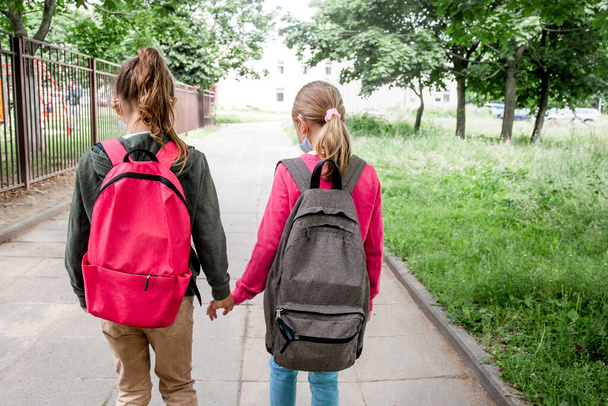 Vista posterior Dos colegialas que van a la escuela con mochilas. Volver a la escuela y concepto de amistad - Foto, imagen