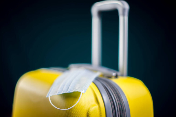 Medical mask on luggage. Travel during coronavirus time. Studio shot - Photo, Image