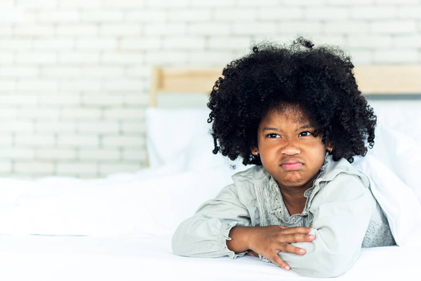 Portraitbilder von afrikanischen Mädchen 5 Jahre alt, Liegen im weißen Bett Zeigt Gesicht Darstellung von Wut und Ressentiments, Konzept für Kinder mit emotionalem Ausdruck. - Foto, Bild