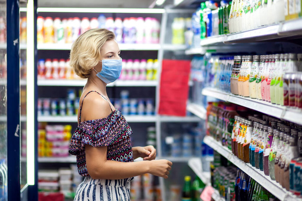 Tıbbi maskeli bir müşteri kadın marketten alışveriş yapıyor. Koronavirüs zamanında yaşam - Fotoğraf, Görsel