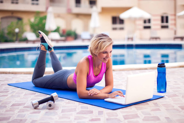 Mladá žena začíná on-line fitness třídy na notebooku venkovní. Lidé, sport a zdravotní péče - Fotografie, Obrázek