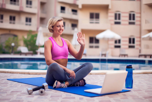 Young woman starting online fitness class on a laptop outdoor. People, sport and healthcare concept - Foto, Imagem