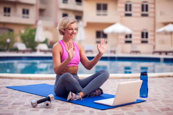 Young woman starting online fitness class on a laptop outdoor. People, sport and healthcare concept - Fotó, kép