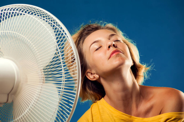 A portrait of woman in front of fan suffering from heat. Hot weather concept - Photo, Image