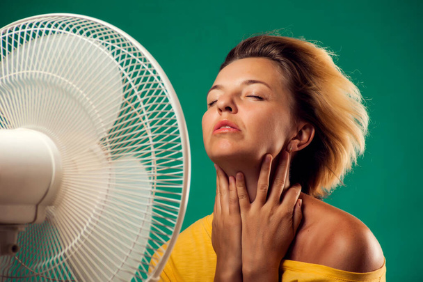 Ein Porträt einer Frau vor einem Ventilator, der unter Hitze leidet. Konzept für heißes Wetter - Foto, Bild