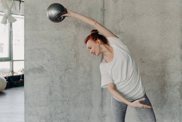 Athletic rude włosy młoda kobieta wykonywania barre ćwiczenia z małym fitball - Zdjęcie, obraz