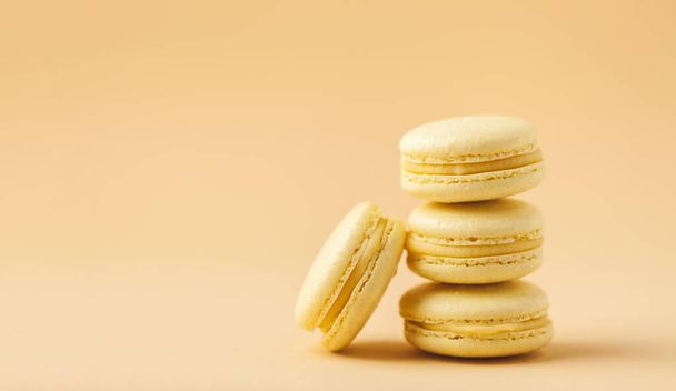 Stack of yellow macaroons with shallow depth of field on the yellow flesh colored background. Macro shot of French sweet dessert cookies. - Fotoğraf, Görsel