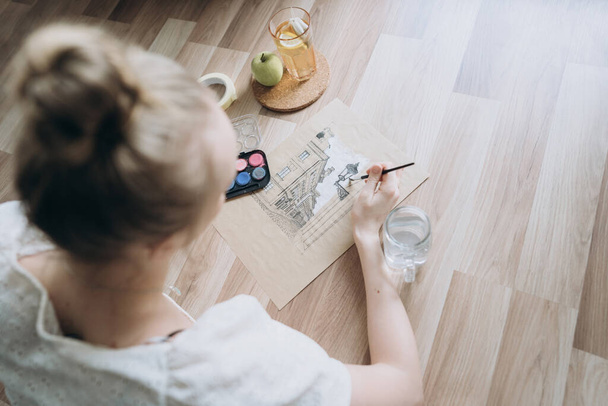 An unrecognizable young female artist in the process of working in a modern interior.A student draws a sketch for an architectural project, uses watercolors.The lifestyle of a modern creative person - Foto, immagini
