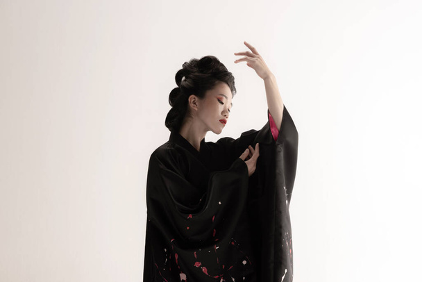Retrato de joven hermosa japonesa, mujer en traje nacional kimono posando aislado sobre fondo de estudio blanco. - Foto, Imagen