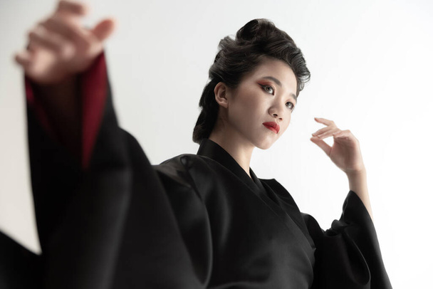 Портрет молодої вродливої японки, жінки в національному вбранні кімоно, яка видає себе за білу студію.. - Фото, зображення