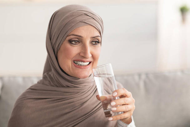 Cheerful Middle-Eastern Mature Woman Drinking Water At Home - Foto, afbeelding